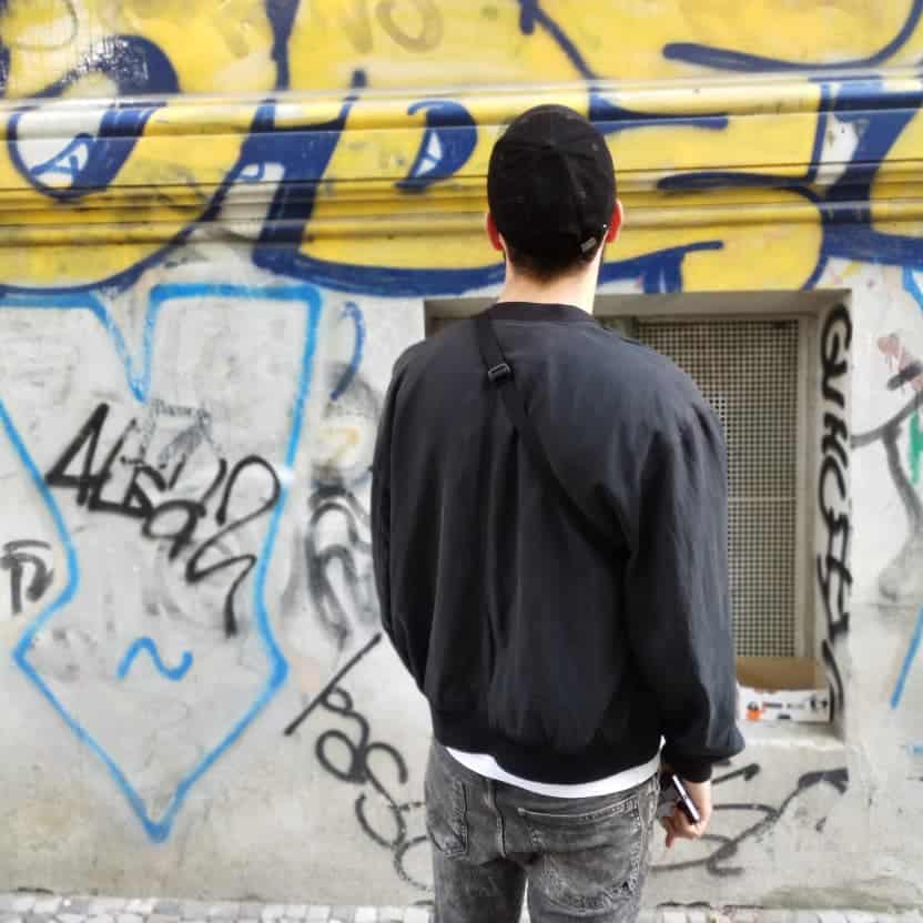 A young guy looking at a wall full of graffiti